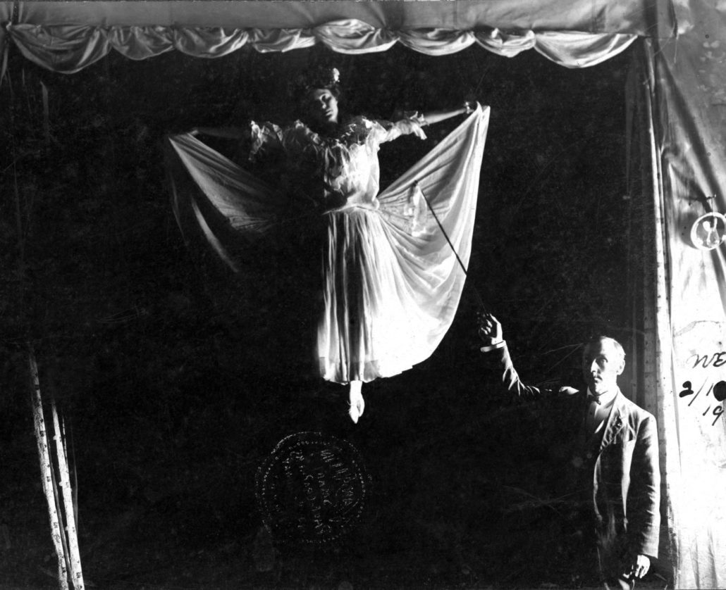 Man pointing to a woman who appears to be floating on a stage