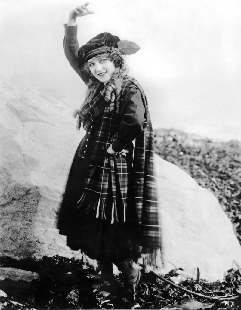 Young woman dressed in plaid with one arm in the air