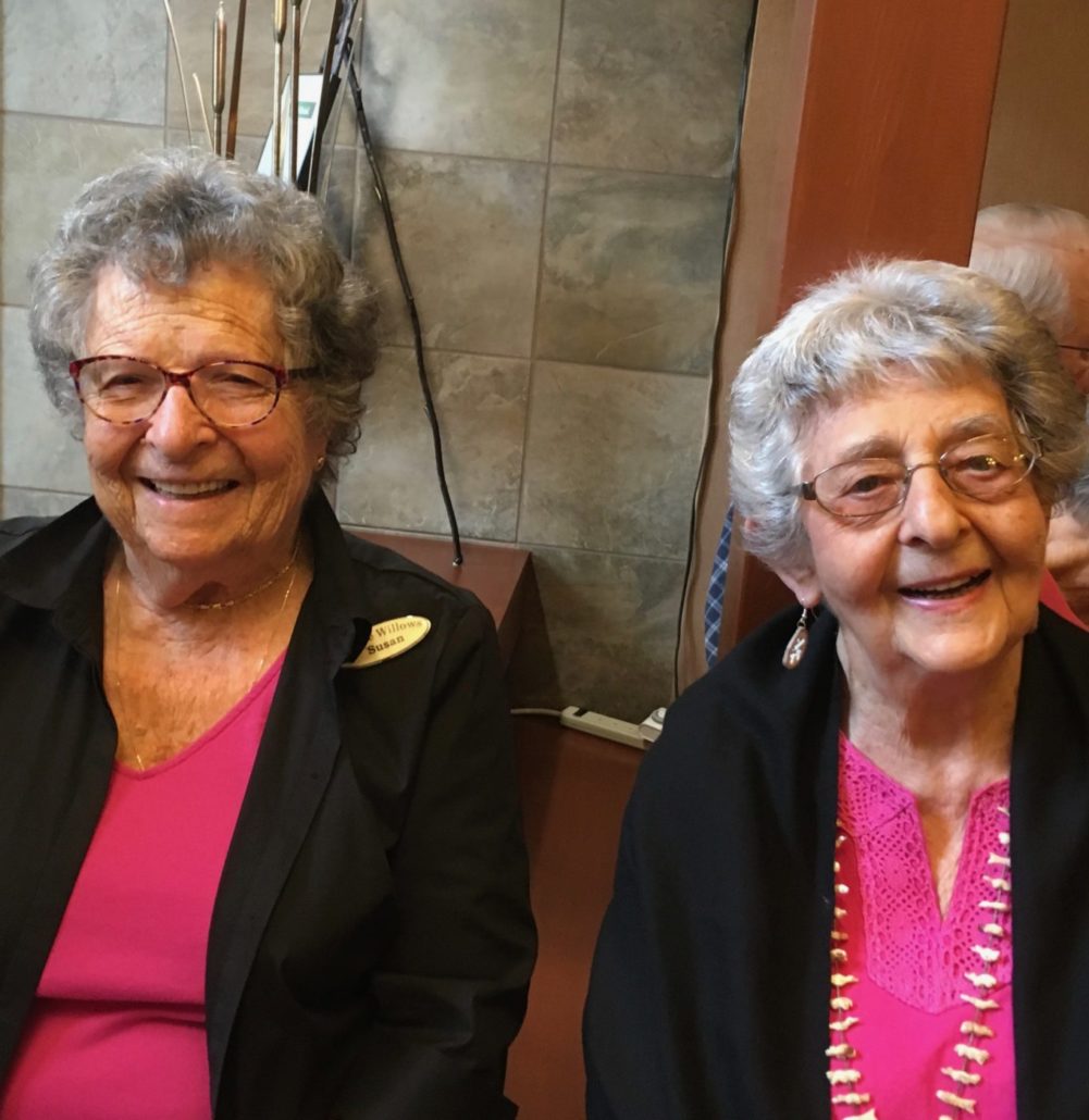 Two women smiling sitting next to each other