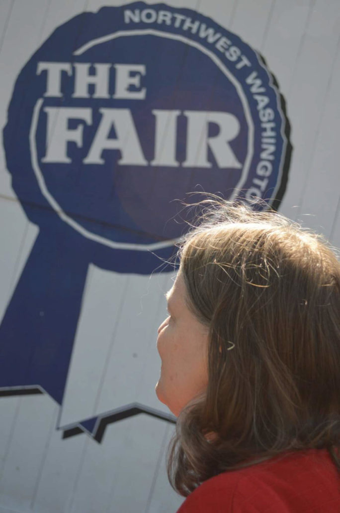 Woman looking away from the camera at a sign that reads "The Fair"