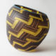 Yellow and brown woven basket design on blown glass tilted vase