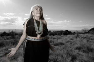Female identified Indigenous elder wearing beaded necklace and a black dress