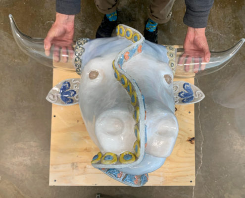 A man holds the glass horns of a bull sculpture