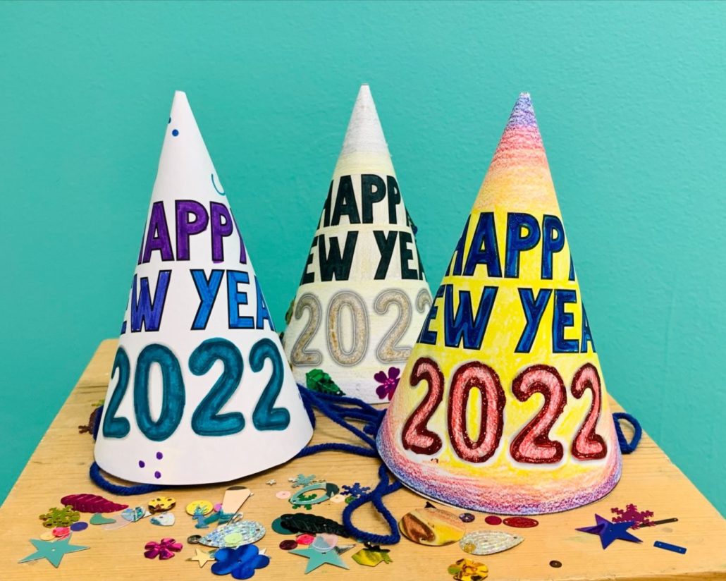 Three paper hats that read Happy New Year 2022