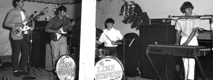 Black and white image of a rock band in the 1960s playing on a stage