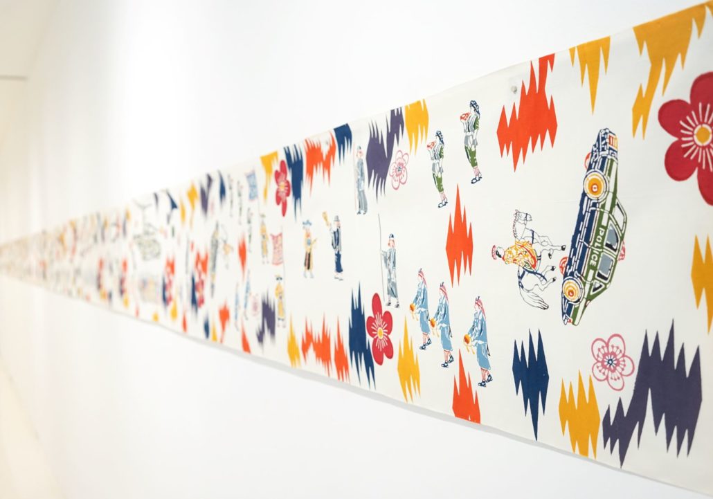 Long horizontal artwork with various colored prints of shapes, people, a car, and a horse